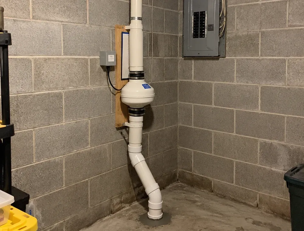 Interior radon mitigation fan and vent piping in a concrete-block basement